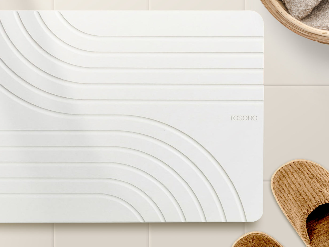 TOSORO Flow Sandstone mat styled on warm tile with a towel basket and slippers
